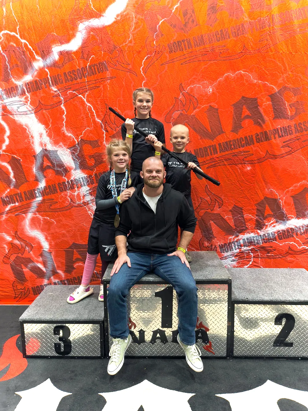 Tier 1 kids with medals on the NAGA podium